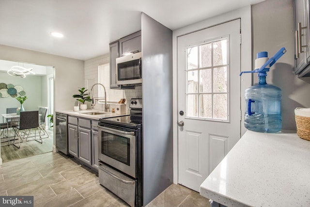 kitchen with appliances with stainless steel finishes, sink, gray cabinetry, and decorative backsplash