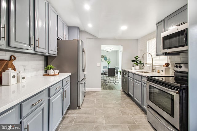 kitchen featuring appliances with stainless steel finishes, sink, gray cabinetry, and backsplash