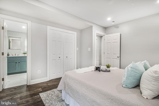 bedroom with ensuite bathroom, dark hardwood / wood-style floors, sink, and a closet