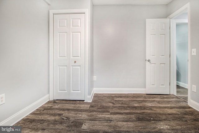 unfurnished bedroom featuring dark wood-type flooring and a closet