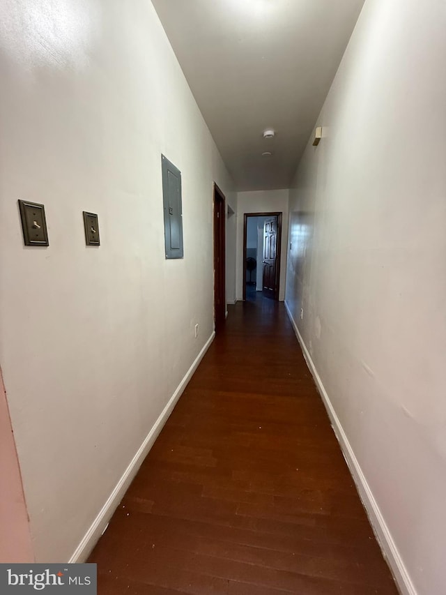 hallway with dark wood-style flooring, electric panel, and baseboards