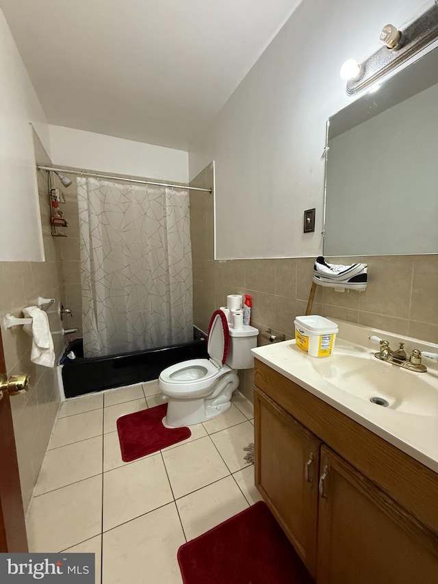 full bathroom with a shower with shower curtain, toilet, tile patterned floors, vanity, and tile walls