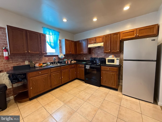 kitchen featuring white microwave, freestanding refrigerator, black / electric stove, under cabinet range hood, and a sink