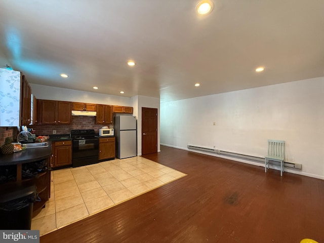 kitchen with electric range, dark countertops, freestanding refrigerator, under cabinet range hood, and a sink