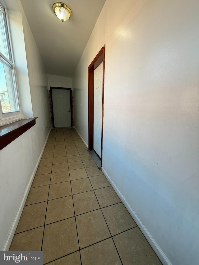 hallway with baseboards and tile patterned floors