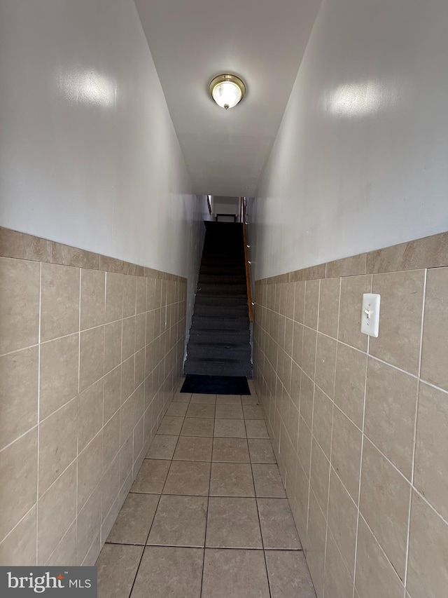 hall with stairway, wainscoting, tile walls, and tile patterned floors