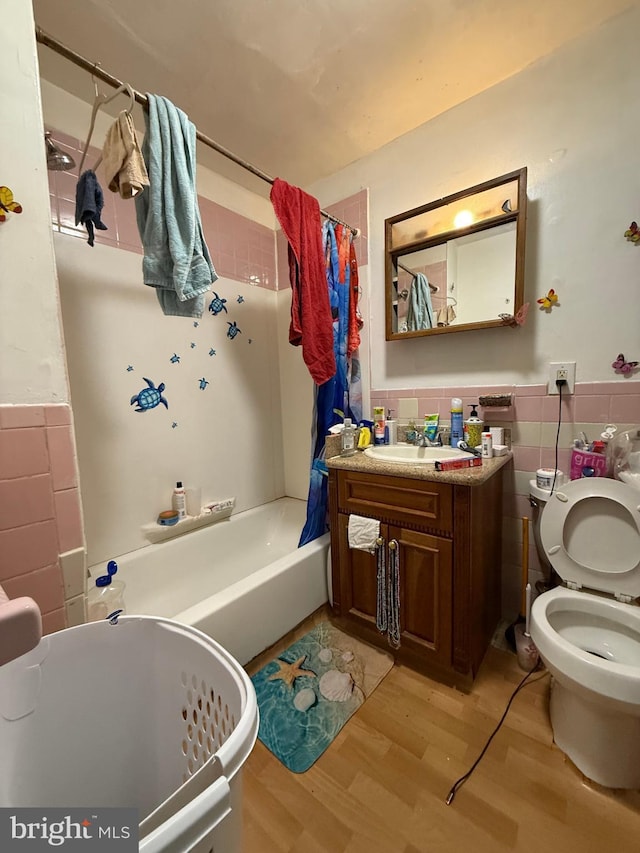 full bathroom with wainscoting, wood finished floors, and tile walls