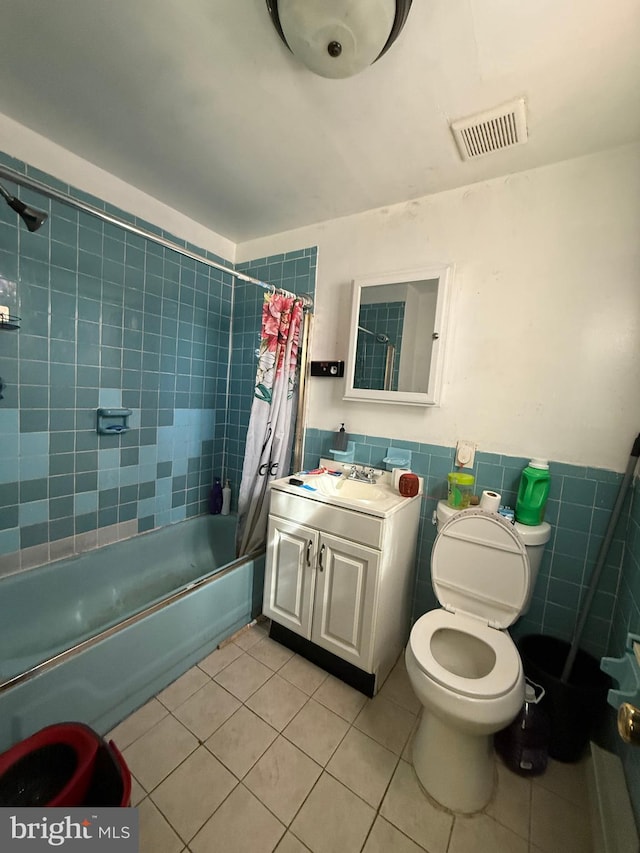 full bathroom featuring a wainscoted wall, tile patterned floors, visible vents, tile walls, and shower / tub combo with curtain