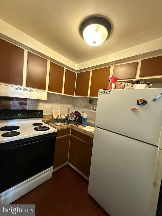 kitchen featuring under cabinet range hood, electric range, a sink, light countertops, and freestanding refrigerator