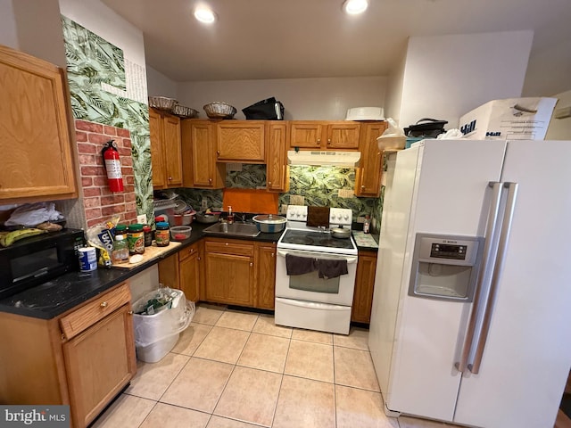 kitchen with light tile patterned floors, tasteful backsplash, a sink, white appliances, and under cabinet range hood