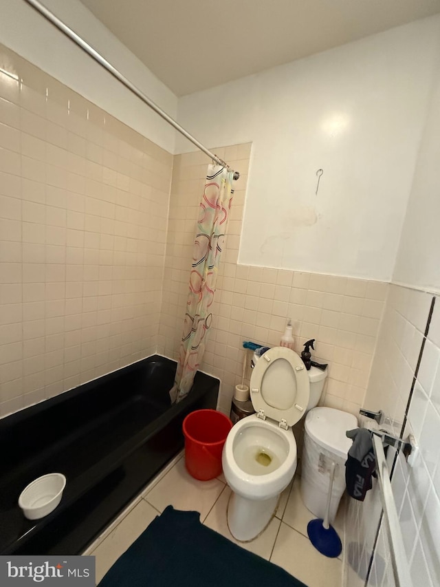 full bathroom with wainscoting, toilet, tile patterned floors, shower / bath combo with shower curtain, and tile walls