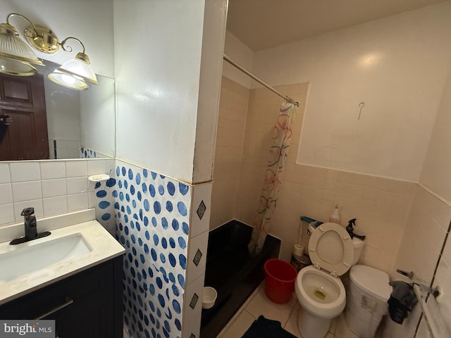 bathroom featuring a stall shower, toilet, tile patterned flooring, vanity, and tile walls