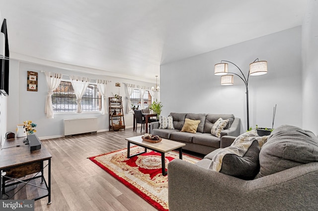 living room featuring hardwood / wood-style flooring, radiator heating unit, and a chandelier