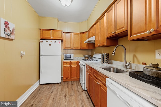 kitchen with light stone counters, sink, white appliances, and light wood-type flooring