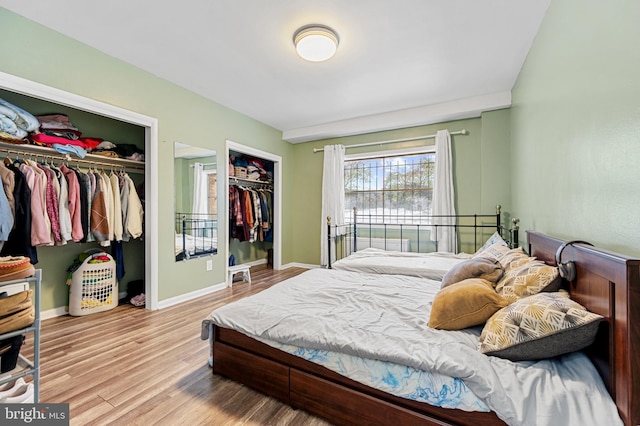 bedroom featuring light hardwood / wood-style flooring and two closets