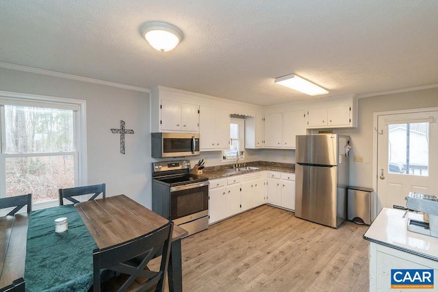 kitchen with sink, white cabinetry, crown molding, light hardwood / wood-style flooring, and stainless steel appliances