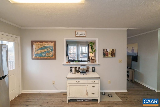 kitchen featuring crown molding, dark wood-type flooring, white cabinets, and stainless steel refrigerator