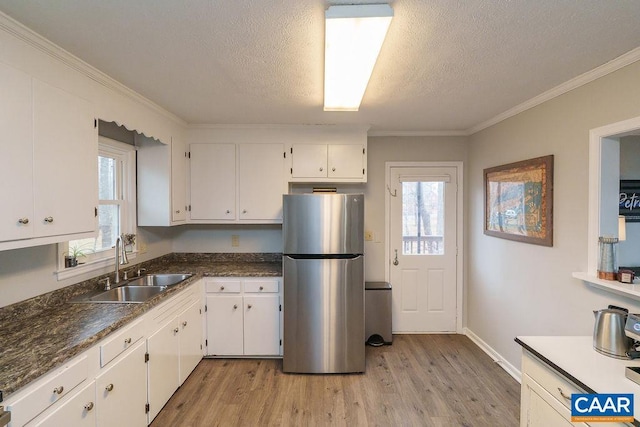 kitchen with stainless steel refrigerator, plenty of natural light, light hardwood / wood-style flooring, and white cabinets