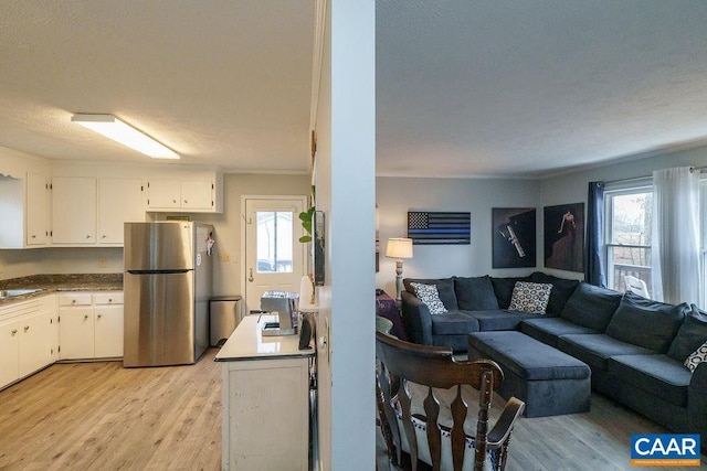 kitchen with sink, white cabinets, stainless steel fridge, crown molding, and light wood-type flooring