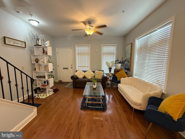 living area with ceiling fan, stairs, and dark wood finished floors