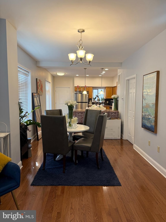 dining space featuring dark wood-style flooring, visible vents, a notable chandelier, and baseboards