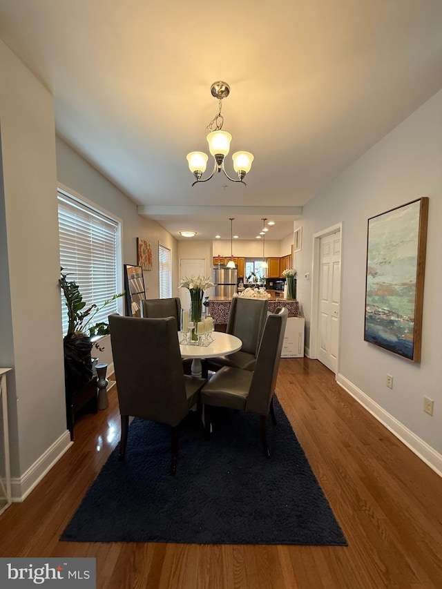 dining area featuring a healthy amount of sunlight, an inviting chandelier, and dark wood-style flooring