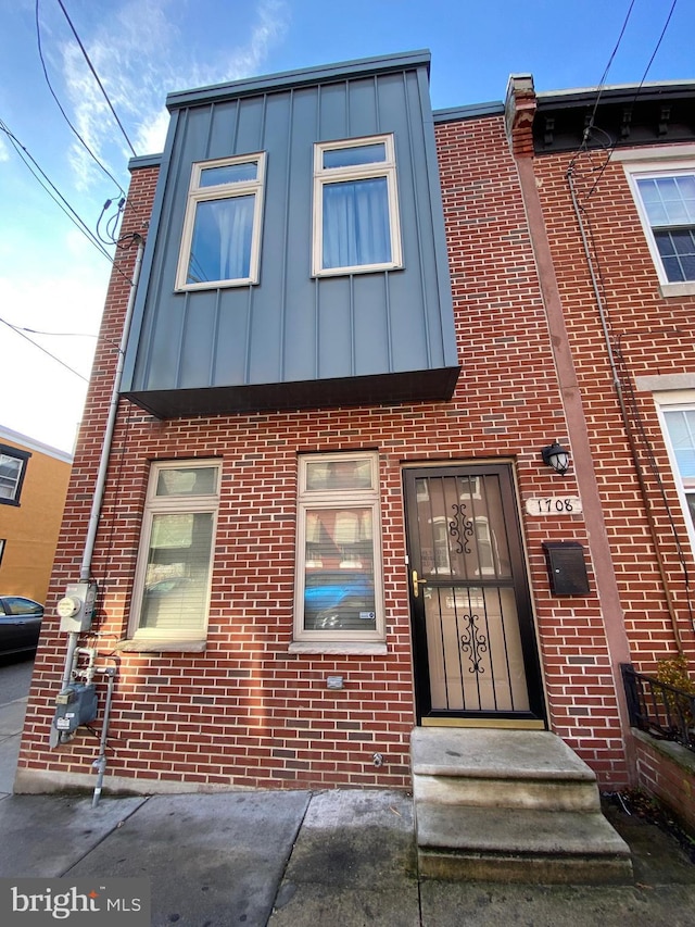 townhome / multi-family property featuring entry steps, board and batten siding, and brick siding