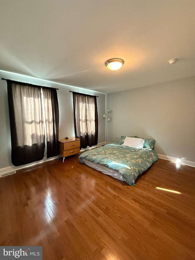 bedroom with visible vents, baseboards, and wood finished floors