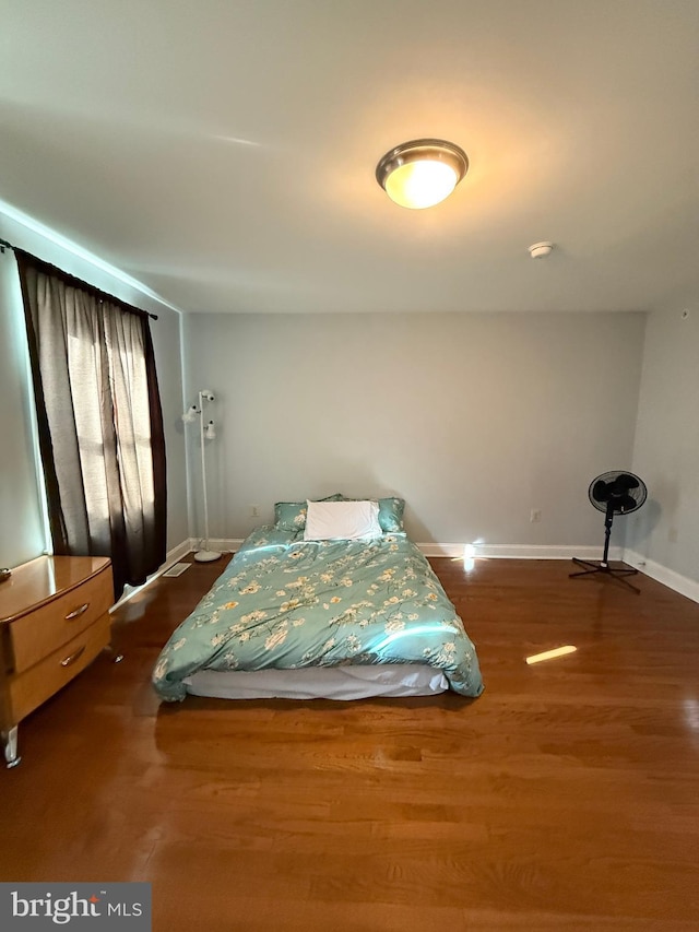 bedroom with dark wood-style flooring and baseboards