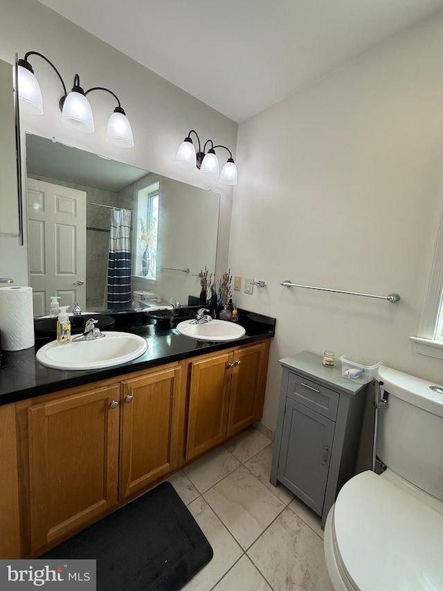 bathroom featuring marble finish floor, double vanity, a sink, and toilet