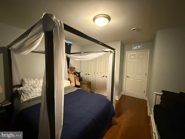 bedroom with dark wood-type flooring and baseboards