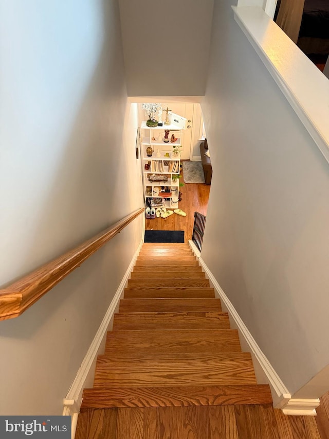 stairway with wood finished floors and baseboards