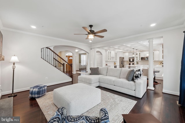 living room featuring ceiling fan, ornamental molding, dark hardwood / wood-style flooring, and ornate columns