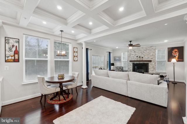 living room with beam ceiling, decorative columns, coffered ceiling, dark hardwood / wood-style flooring, and a stone fireplace