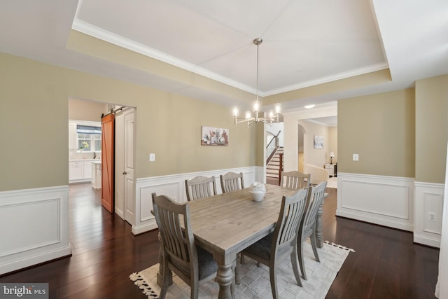 dining area featuring dark hardwood / wood-style floors, a tray ceiling, a chandelier, and crown molding