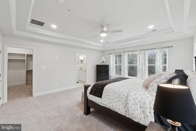 bedroom with light carpet, a walk in closet, ornamental molding, and a raised ceiling