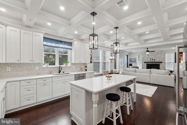 kitchen with a kitchen island, a fireplace, dishwasher, white cabinetry, and sink