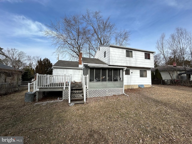 rear view of property with a lawn, a sunroom, and a deck