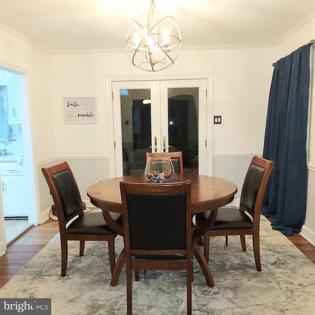 dining room featuring hardwood / wood-style flooring, ornamental molding, a chandelier, and french doors