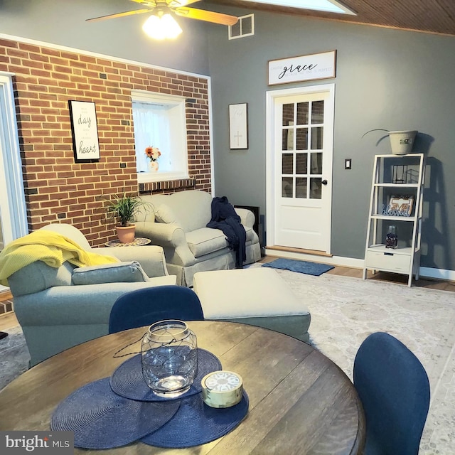 living room with hardwood / wood-style flooring, vaulted ceiling, brick wall, and ceiling fan