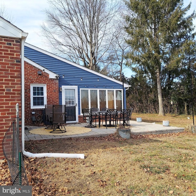 back of property with a lawn and a patio