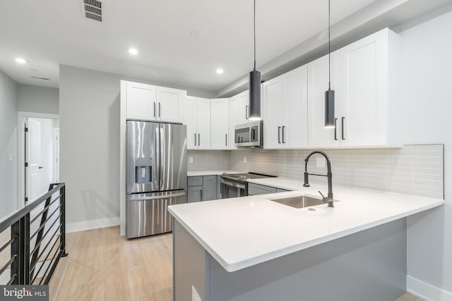 kitchen featuring stainless steel appliances, tasteful backsplash, light countertops, visible vents, and a sink