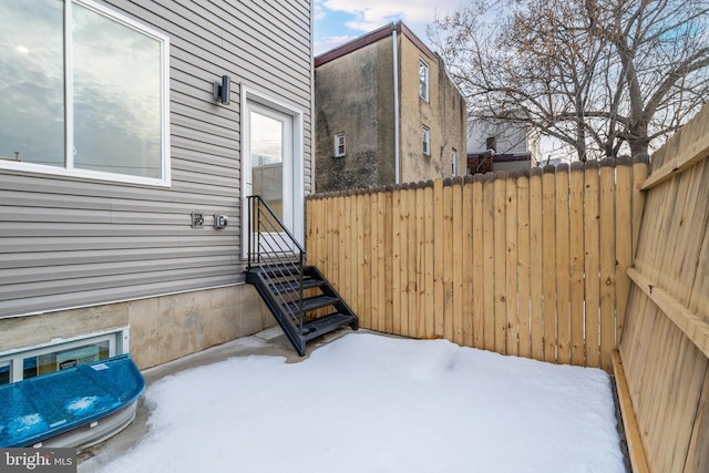 snow covered patio featuring entry steps and fence