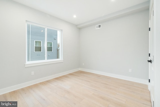 spare room with light wood-style flooring, visible vents, and baseboards