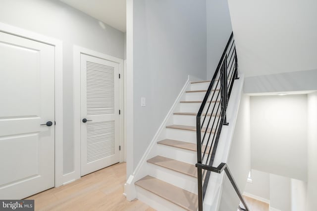 staircase featuring baseboards and wood finished floors