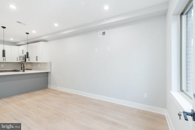 kitchen featuring light countertops, tasteful backsplash, stainless steel microwave, and visible vents