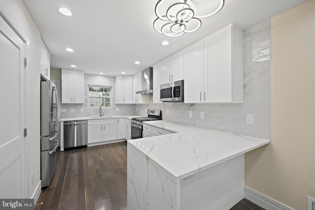 718 Collington Ave, Baltimore, MD 21205 - kitchen with wall chimney range hood, appliances with stainless steel finishes, white cabinetry, light stone countertops, and kitchen peninsula