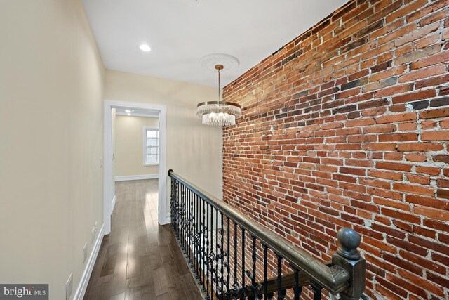 718 Collington Ave, Baltimore, MD 21205 - hallway with a notable chandelier, dark wood-type flooring, and brick wall