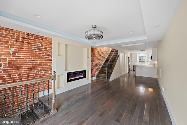 718 Collington Ave, Baltimore, MD 21205 - unfurnished living room with a tray ceiling, dark hardwood / wood-style floors, and brick wall
