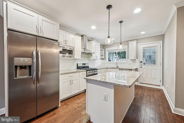 kitchen featuring white cabinets, stainless steel appliances, decorative light fixtures, and wall chimney range hood